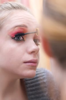 woman applying make up in front of mirror