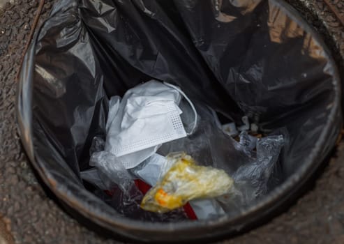 The end of coronavirus. Stop Covid 19. People discard surgical protective face mask in a public trash bin. Dirty used medical mask laying in a contaminated waste bin or garbage can during an epidemic