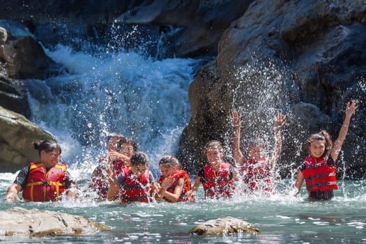 CIUCAS, CLUJ COUNTY, ROMANIA - JULY.11.2016: Children from a socially disadvantaged community taken on a holiday trip playing in the water at a small waterfall, dressed in life jackets
