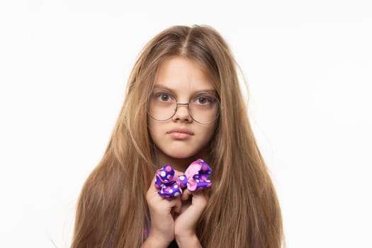 Closeup portrait of a scared girl with a blue bow in her hands