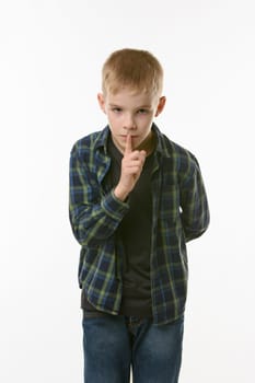 Portrait of teenager boy showing quieter sign, pressing index finger to his mouth