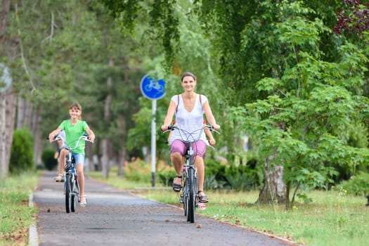 Mom and daughter ride a bike in the park