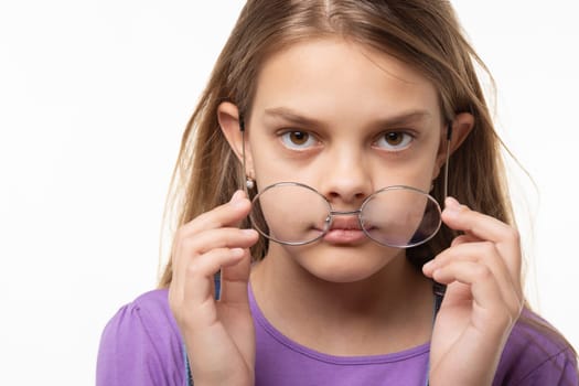 Teen girl takes off glasses, close up