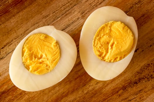 Hard boiled eggs, sliced in halves on wooden background.