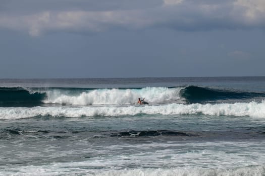 Young caucasian man surfs the ocean wave and makes a lot of splashes into the camera. Nyang Nyang Surf Spot in Bali, Indonesia. The surfer falls into the ocean waves. Man rides the wave at sunny day.