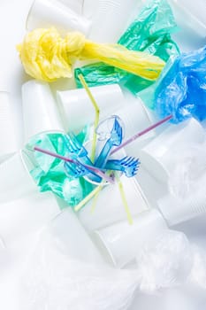 Assortment of disposable plastic, cups, cutlery, bags and drinking straws. Environmental concept. Non-compostable waste