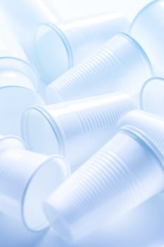 Disposable white plastic cups as background. Environmental concept. Non-compostable waste. In blue tone.