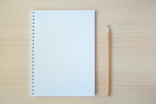 Pencil with open clear notepad on wooden table.