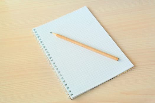 Pencil with open clear notepad on wooden table.