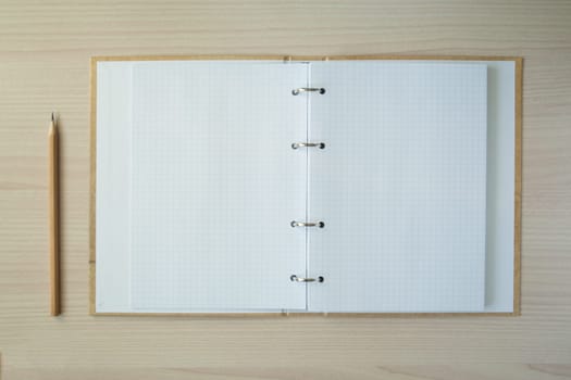 Pencil with open clear notepad on wooden table.