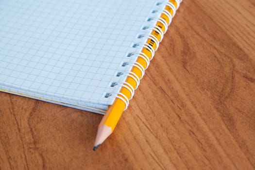 Pencil with open clear notepad on wooden table.