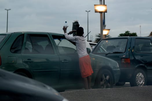 salvador, bahia / brazil - december 4, 2006: child is seen working washing vehicle windshield at traffic lights in the city of Salvador.