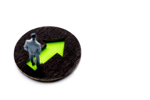 Miniature figurine posed as visualising businessman standing on green arrow marking the way moving forward, minimalist abstract concept image with copy space on the right