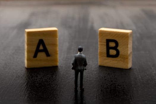 Miniature figurine posed as businessman making decision on Solution A versus B, minimalist abstract concept image