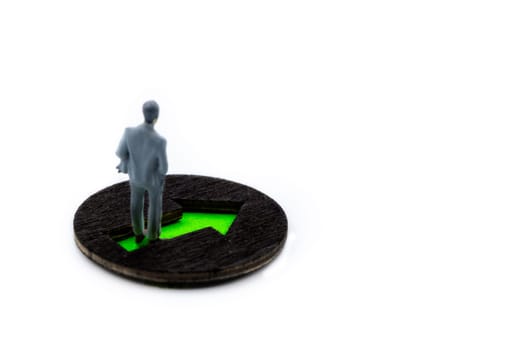 Miniature figurine posed as visualising businessman standing on green arrow marking the way moving forward, minimalist abstract concept image with copy space on the right