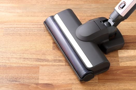 Head of modern vacuum cleaner on wooden floor background. Close up.