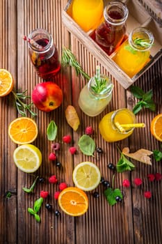 Assortment of juices and lemonades with fruits and herbs on wooden table