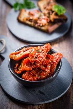 Sun dried tomato with olive oil as antipasto with tapenade and bruschetta in background