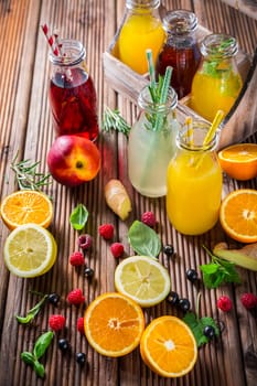 Assortment of juices and lemonades with fruits and herbs on wooden table
