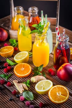 Assortment of juices and lemonades with fruits and herbs on wooden table