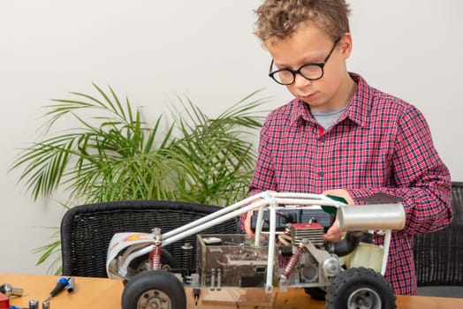 little boy repairing a model radio-controlled car at home