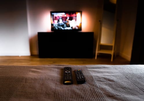Remote Controls for Wireless Smart Television, DVB-T2, DVD, K1, KI Plus, KII Pro, DVB-S2, Android TV Box, Set-Top Box, Satellite Receiver, HDTV, Media Player on bed in cozy room against TV background
