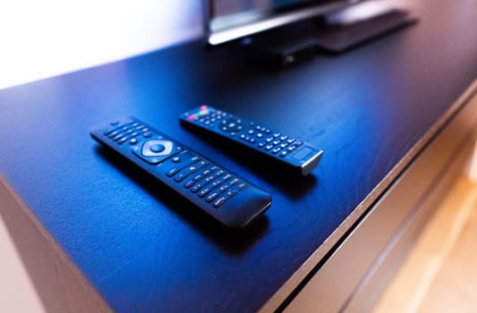Remote Controls for Wireless Smart Television, DVB-T2, DVD, K1, KI Plus, KII Pro, DVB-S2, Android TV Box, Set-Top Box, Satellite Receiver, HDTV, Media Player on wooden TV stand against TV background