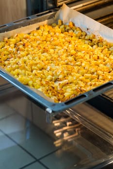 Baking tray with golden roasted potatoes in the open oven