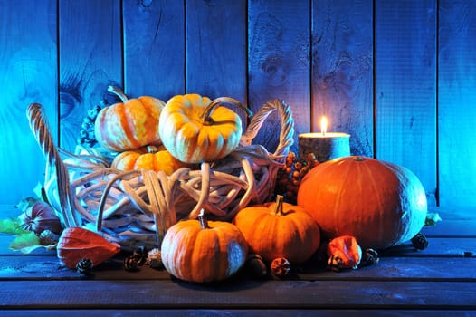 Halloween pumpkins in rattan basket in front of an old weathered wooden wall in blue light