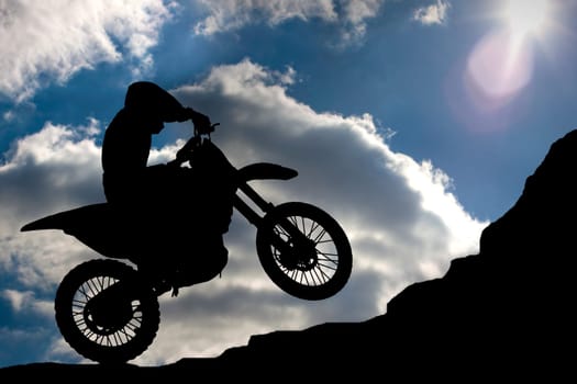 Motocross - silhouette with a rock and blue sky with sun
