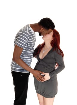 A young couple kissing and holding the hand on her tummy, .standing in profile, isolated for white background..