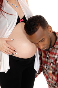 An African American man holding his ear on his wife's baby belly,.listening for his heartbeat, isolated for white background..