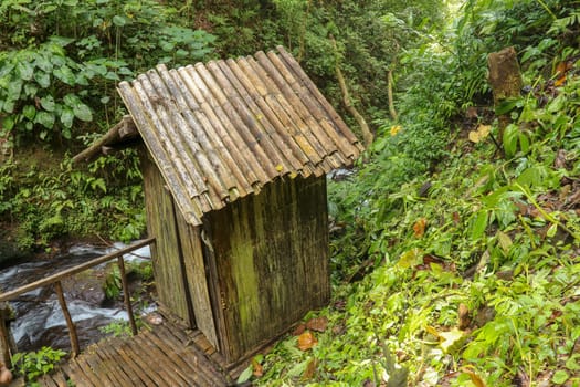 Changing room built of bamboo trunks by a river in a tropical rain forest. Small house at Spray Waterfall on Bali Island high in the mountains. Valley with river in tropical jungle.