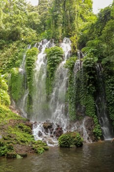Spray waterfall in Bali island, Indonesia. Scenic waterfall high in the mountains. Having fun in the wild nature. Waterfalls in jungle. Bali Travel Concept. Lifestyle. Travel photography.
