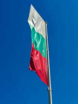 Bulgarian flag waving on blue sky background. The location is Obzor, Bulgaria. Flag of Bulgaria against the clear sky.