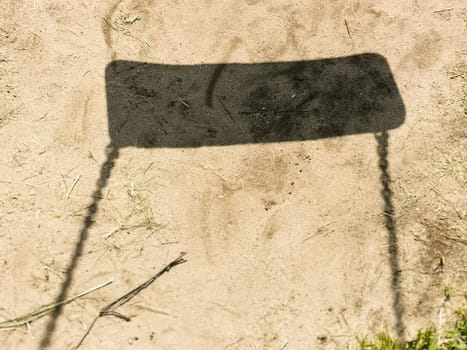 Shadow of empty swing at playground. loneliness and childhood nostalgia, negative birthrate concept. Corona virus causes empty playgrounds