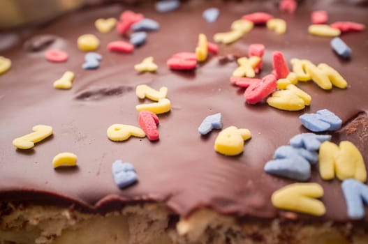 Homemade chocolate cake covered with glimmer sugar letters. Closeup