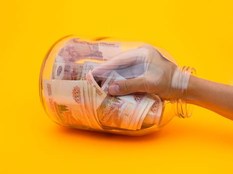 Hand climbed into a glass jar full of five thousandth bills