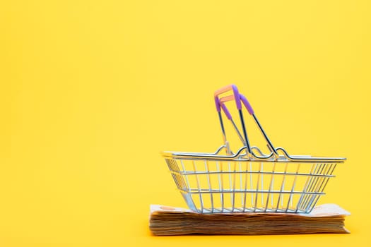 On a bundle of notes lies an empty grocery basket with raised handles