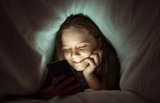 Young girl using a phone in bed