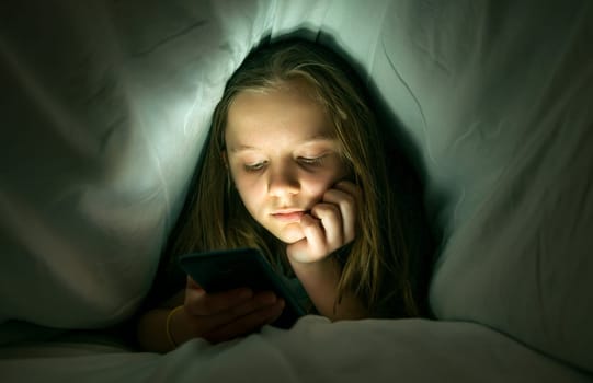 Young girl using a phone in bed