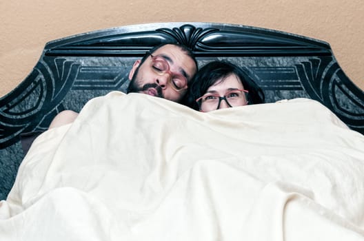Funny couple with glasses in the bed