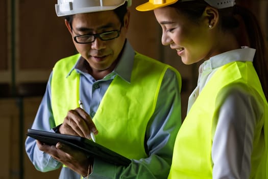 Asian warehouse manager discuss with warehouse worker using digital tablet to assign job inside distribution warehouse. Reopening business warehouse technology and logistic concept.