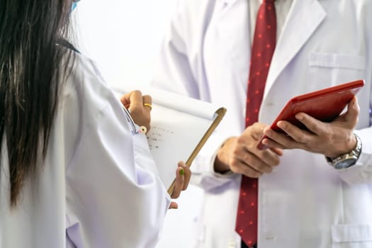 close up of senior doctor giving his younger colleagues a piece of advice concerning the diagnosis in clinic hospital. Healtcare teamwork concept.