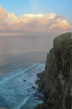 Beautiful Panoramic view of an Iconic Famous Place, Uluwatu Temple, during a vibrant summer sunrise. Amazing views at Pura Luhur Uluwatu temple in Bali Island. Nice colourful sunset with clouds.