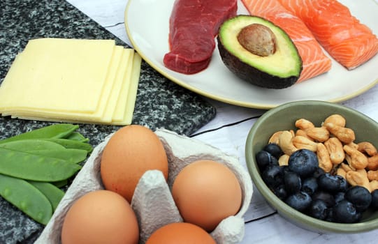 low carb ketogenic gluten free paleo style diet protein based meat fish dairy eggs veg berries and nuts background with copy space