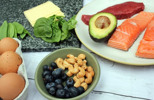 low carb ketogenic gluten free paleo style diet protein based meat fish dairy eggs veg berries and nuts background with copy space