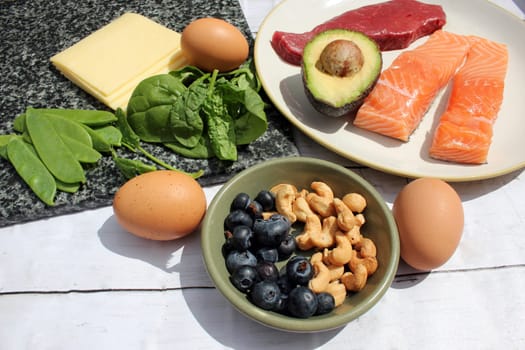 low carb ketogenic gluten free paleo style diet protein based meat fish dairy eggs veg berries and nuts background with copy space