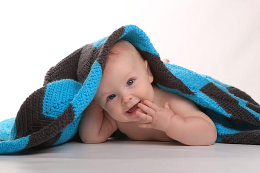 Adorable Baby Smiling Lying on Stomach With Blanket on White Background