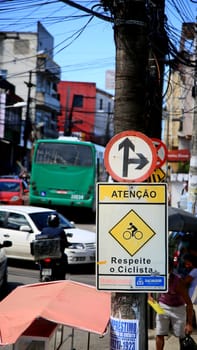 salvador, bahia / brazil - july 1, 2020: indicative traffic sign to go ahead or turn left and another indicating a cycling area is seen in the neighborhood of Pernambues in the city of Salvador